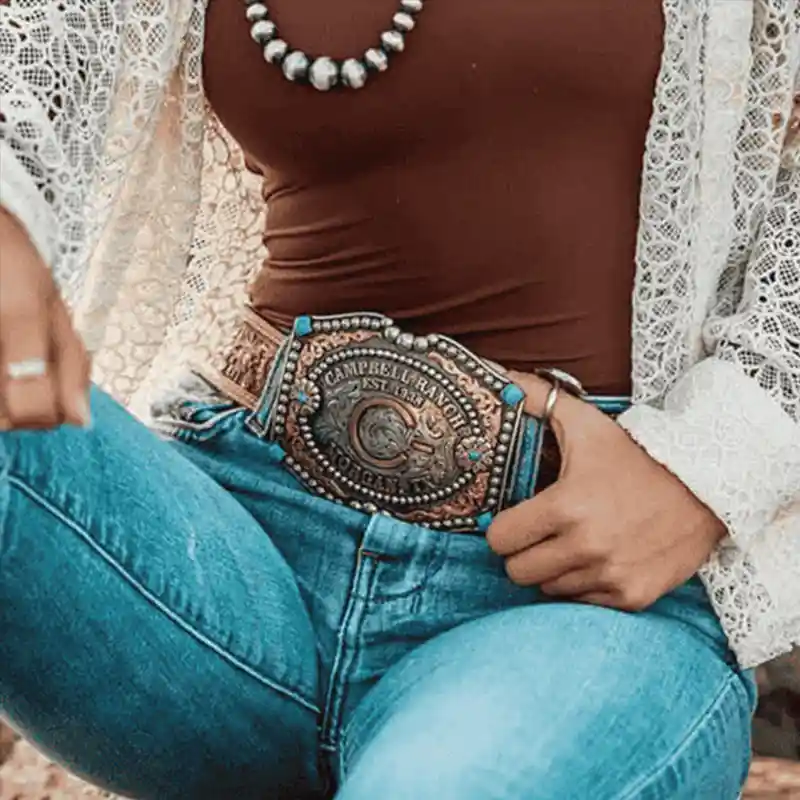 Woman wearing a personalized western belt buckle with a ranch brand and turquoise stones